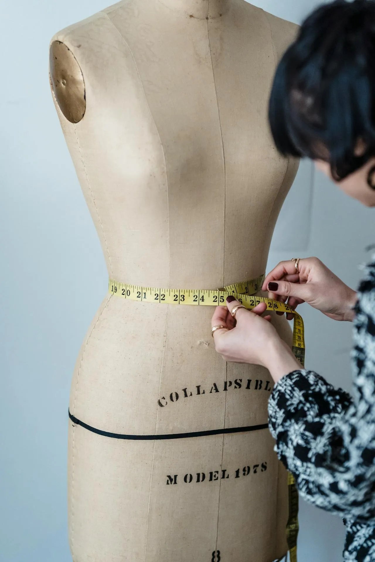 Maniquí indicando con un metro cómo medir el contorno de cintura.