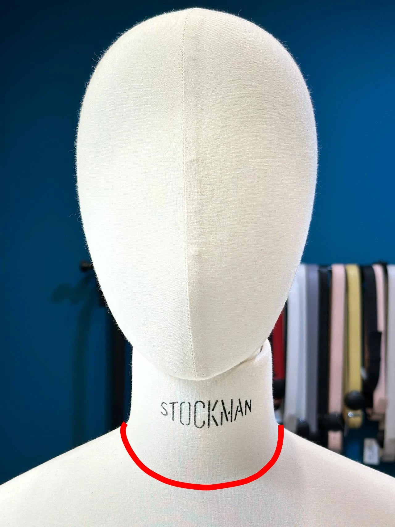 Maniquí de costura Stockman con una línea roja curva marcada en la base del cuello indicando cómo medir el contorno de cuello.