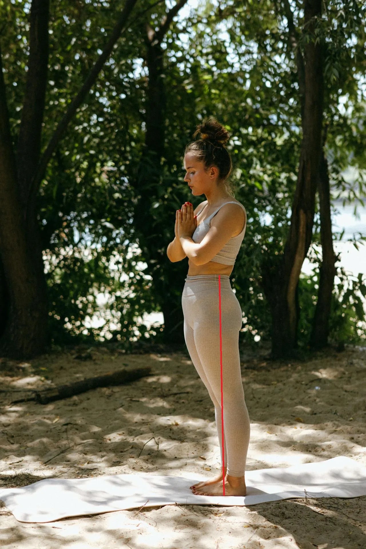 Mujer de perfil con ropa ajustada indicando con una línea roja vertical cómo medir el largo lateral del pantalón desde la cintura hasta el suelo.