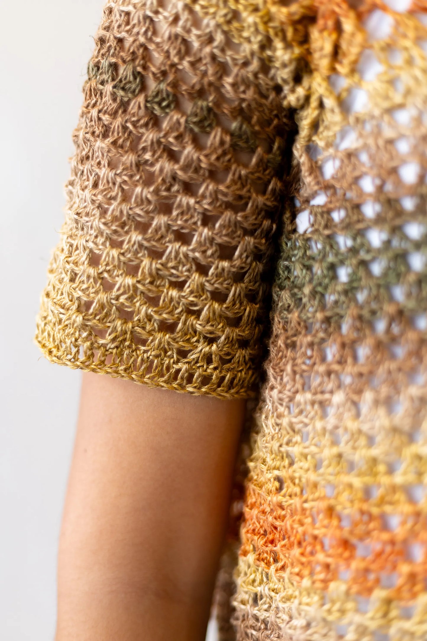 Vista detalle manga del Jersey Belleza tejido a crochet en tonos naranjas y verdes