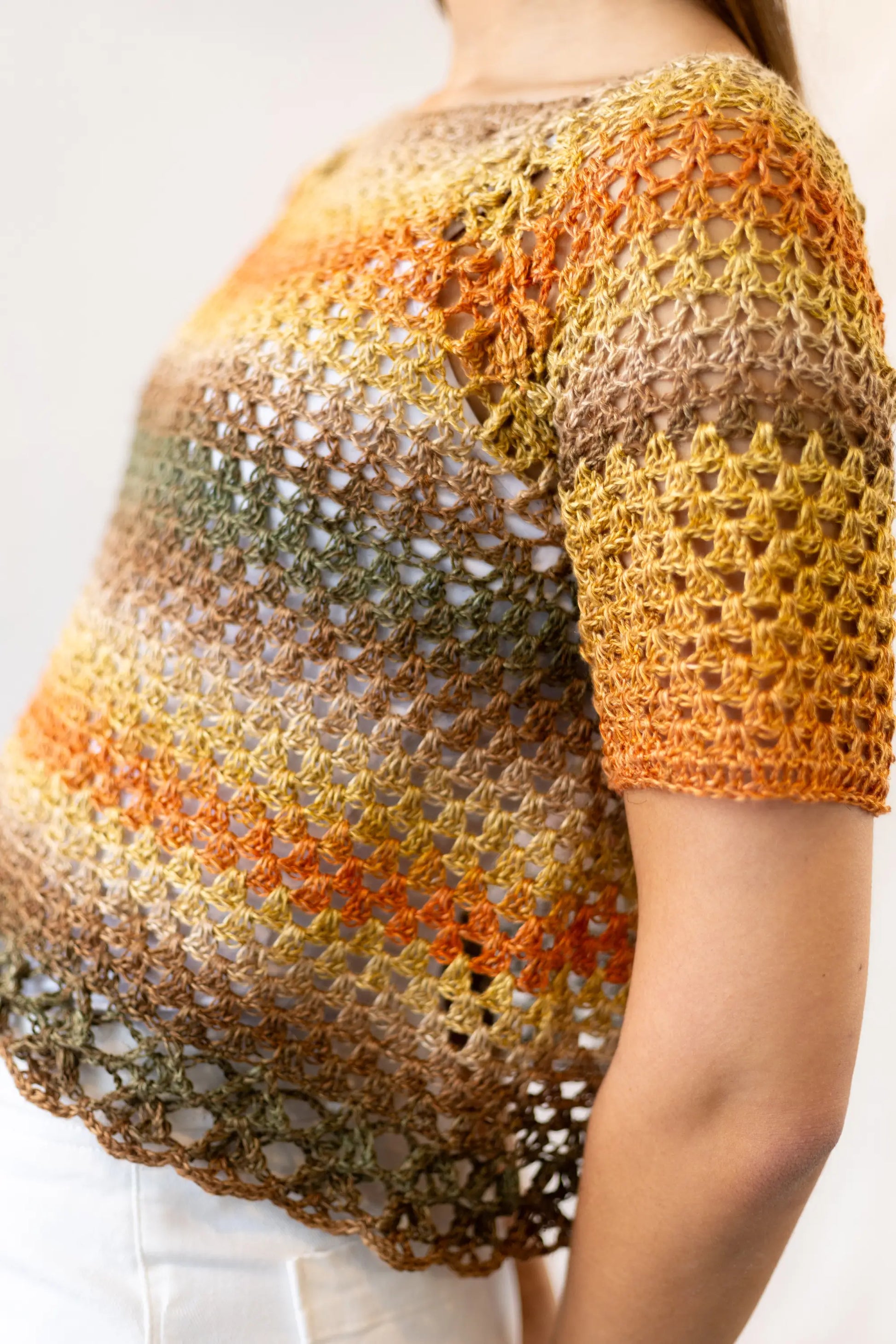 Vista detalle lateral delantero del Jersey Belleza tejido a crochet en tonos naranjas y verdes