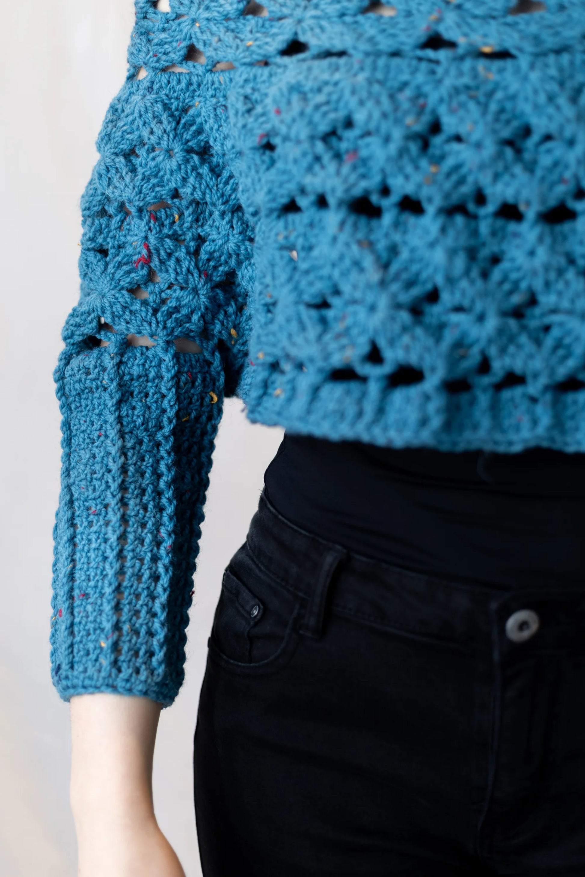 Vista detalle de largo de la manga del Poncho Malala tejido a crochet con lana 100% de color azul y largo hasta cintura