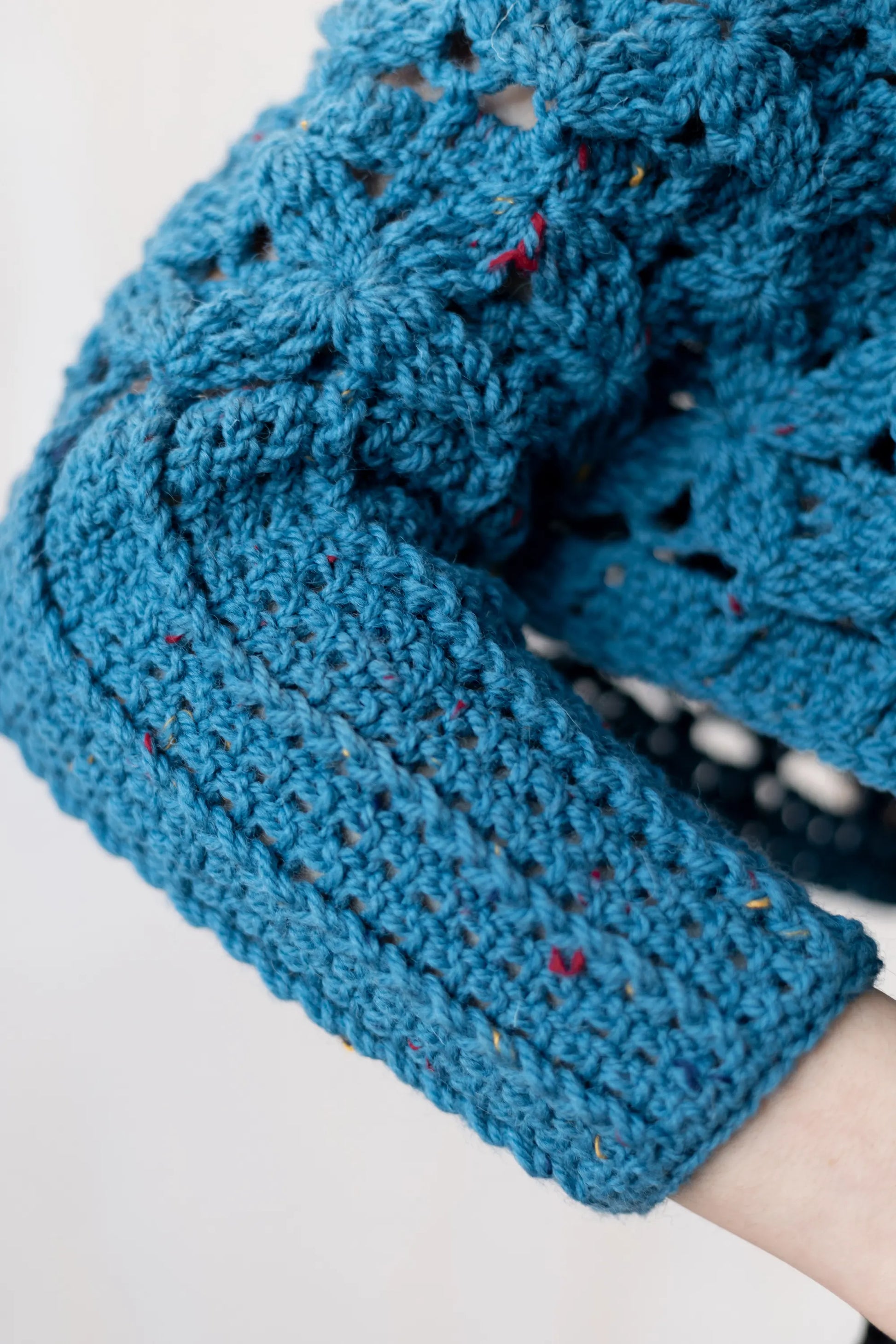 Vista detalle de la manga del Poncho Malala tejido a crochet con lana 100% de color azul y largo hasta cintura