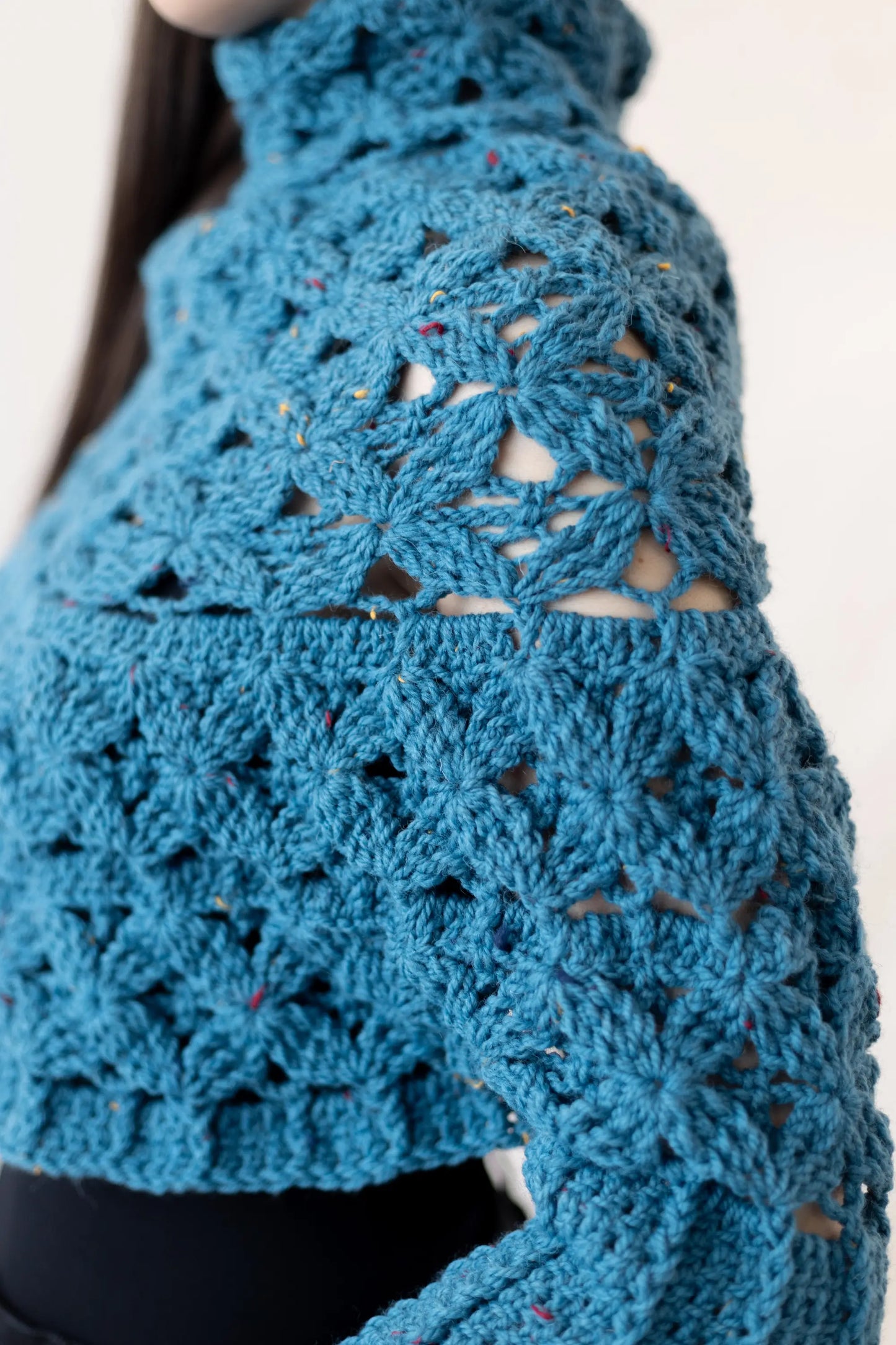 Vista detalle de la textura floral de la manga del Poncho Malala tejido a crochet con lana 100% de color azul y largo hasta cintura